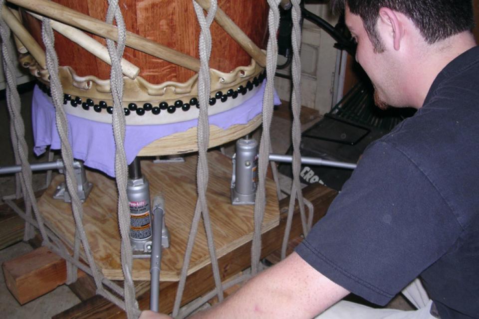 Closeup over the shoulder of a man checking the tension of the stretching rig.